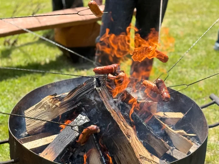 Kiełbaski pieczone nad ogniem w palenisku na terenie zagrody